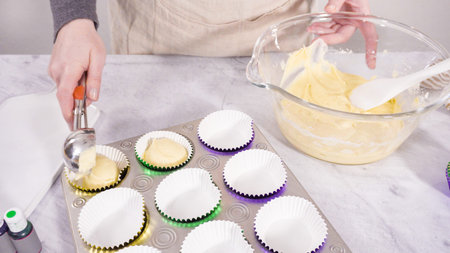 Step by step. Scooping cupcake batter into a foil cupcake liners to bake vanilla Mardi Gras...