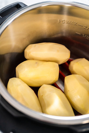 Mashed potatoes. Cooking whole peeled potatoes in a pressure cooker to make mashed potatoes.の写真素材