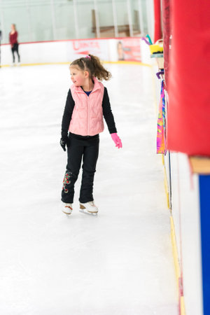 Little girl practicing figure skating elements on indoor ice skating rink.の写真素材