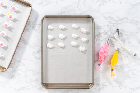 Piping meringue with piping bags into the baking sheet lined with parchment paper to bake Easter...