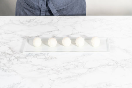 Peeled hard-boiled eggs on a white serving plate.の写真素材