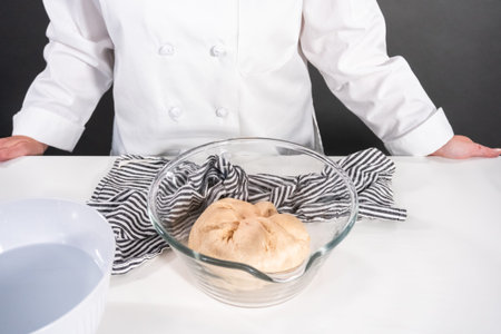 Mixing dough in a glass mixing bowl to bake the cinnamon rolls.