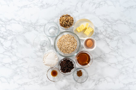 Flat lay. Measured ingredients in glass mixing bowls to bake soft oatmeal raisin walnut cookies.の写真素材