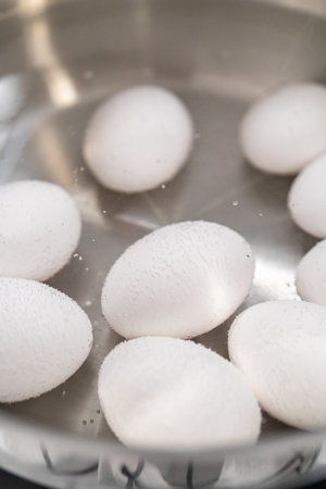 Boiling white eggs in a cooking pot to prepare hard-boiled eggs.の写真素材