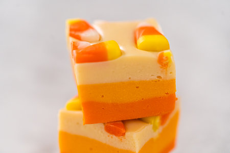 Homemade candy corn fudge square pieces stacked on a kitchen counter.の写真素材