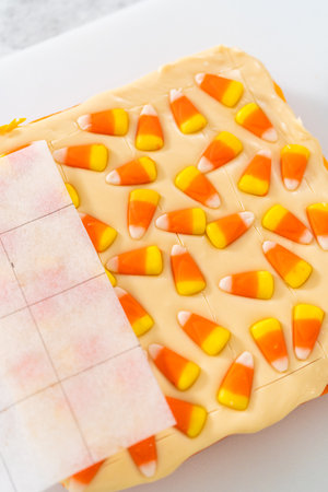 Scoring candy corn fudge using a parchment paper template for cutting into small pieces.の写真素材
