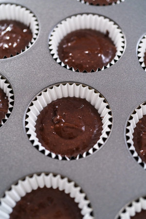 Scooping chocolate cupcake dough into the cupcake liners.