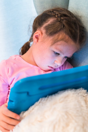 Little girl reading books on her tablet at homeschool.の写真素材