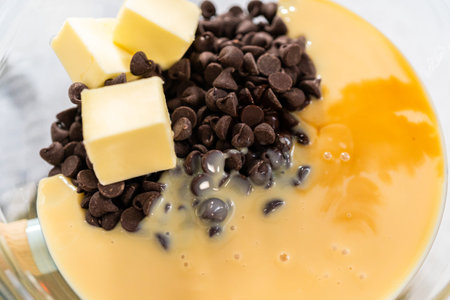 Melting chocolate chips and other ingredients in a glass mixing bowl over boiling water to prepare...