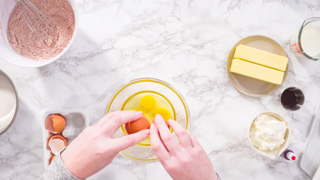 Flat lay. Step by step. Mixing wet ingredients in a glass mixing bowl to bake red velvet cupcakes.
