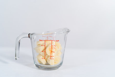 Slicing riped banana in a glass measuring cup.の写真素材