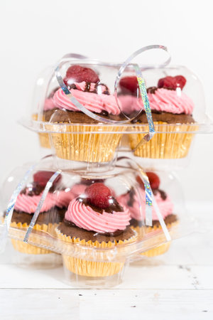 Packaging gourmet chocolate raspberry cupcakes into clear plastic boxes.の写真素材