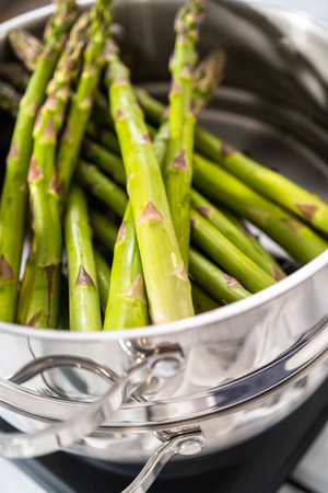Steaming fresh asparagus in stainless steel steaming pot.の写真素材