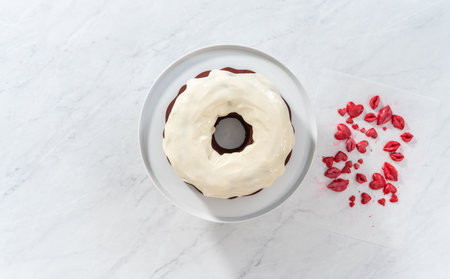 Flat lay. Decorating red velvet bundt cake with chocolate lips and hearts over cream cheese glaze.の写真素材