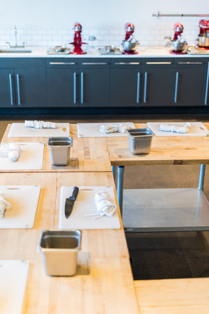 Tables prepared with white cutting boards and aprons for cooking class.の写真素材