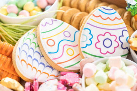 Assembling charcuterie board with Easter candies, cookies, and marshmallows.