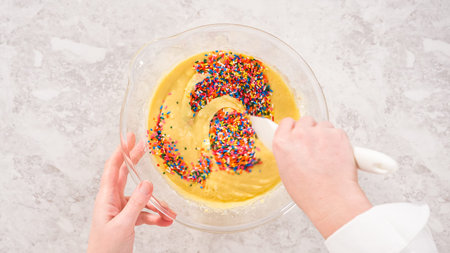 Flat lay. Step by step. Folding into the cake batter rainbow sprinkles to bake funfettti bundt cake.