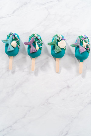Mermaid cakesicles with drizzled chocolate, chocolate mermaid tails, seashells, and sprinkles.の写真素材