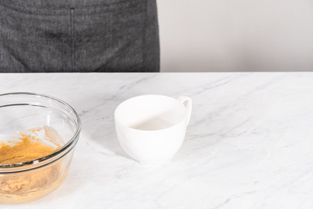 Pouring cake batter into the mug to prepare pumpkin mug cake.の写真素材