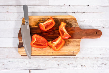 Mincing organic red bell peppers on a wood cutting board.の写真素材