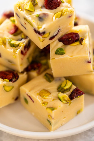 Homemade cranberry pistachio fudge square pieces on a kitchen counter.の写真素材