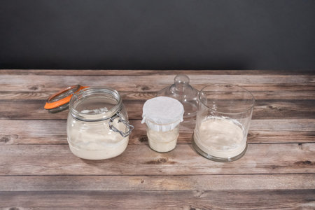 Feeding sourdough starter in a glass mason jar for baking artisan bread.の写真素材