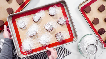 Step by step. Flat lay. Unbaked chocolate cookies on a baking sheet lined up with silicone liner.