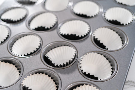 Scooping cupcake batter with dough scoop into a baking pan with liners to bake American flag mini...