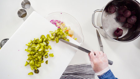 Flat lay. Step by step. Cutting cookies vegetables on a white cutting board for vinaigrette salad.の写真素材