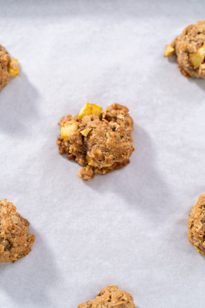 Freshly baked apple oatmeal with apple chunks cookies on a baking sheet lined with parchment paper.の写真素材