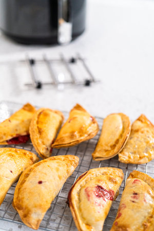 Freshly baked sweet cherry empanadas in the air fryer on the kitchen counter.