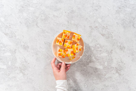 Flat lay. Homemade candy corn fudge square pieces on a white plate.の写真素材