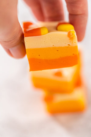 Homemade candy corn fudge square pieces stacked on a kitchen counter.の写真素材