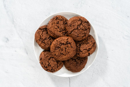 Flat lay. Freshly baked double chocolate chip cookies on a white plate.の写真素材