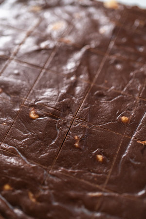 Scoring chocolate macadamia fudge using a wheel dough cutter for cutting into small square pieces.の写真素材