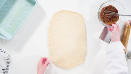 Flat lay. Rolling dough with a french rolling pin to bake cinnamon rolls.