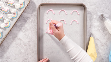 Flat lay. Step by step. Piping meringue mix into unicorn-shaped pops on a baking sheet lined with parchment paper.の写真素材