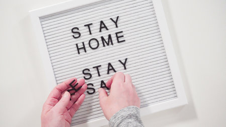 Flat lay. STAY HOME and STAY SAFE sign on message board with a homemade face mask.の写真素材