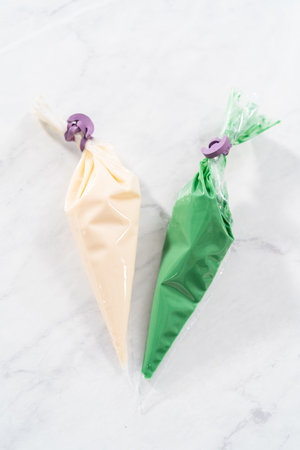Melted white and green chocolate in piping bags.の写真素材
