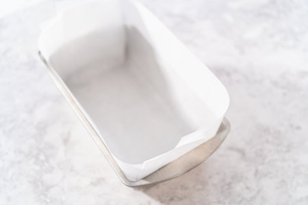 Lining loaf pan with parchment paper to make meatloaf.の写真素材