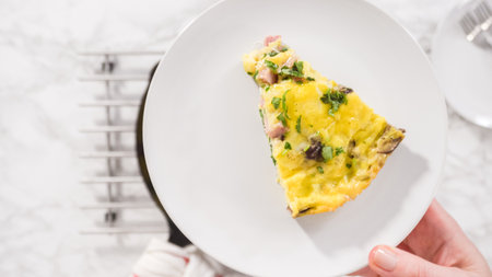 Flat lay. Step by step. Slicing freshly baked spinach and ham frittata in cast iron skillet.の写真素材