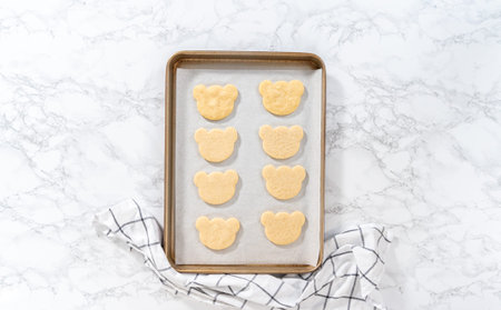 Flat lay. Freshly baked panda-shaped shortbread cookies on a baking sheet.