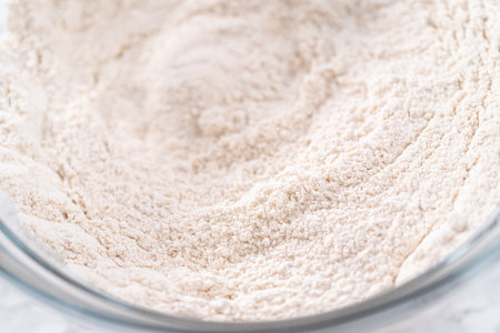 Mixing ingredients in a large glass mixing bowl to bake pumpkin bunt cake.の写真素材