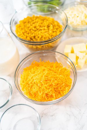 Measured ingredients in glass mixing bowls to prepare macaroni and cheese with broccoli.