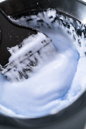 Mixing hair color dye in a black mixing bowl with a brush.の写真素材