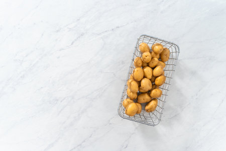 Flat lay. Pressure Cooker Baked Potatoes. Raw potatoes in a wire basket on the kitchen counter.の写真素材