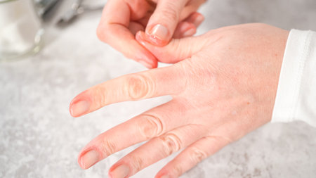 Woman finishing her manicure at home with simple manicure tools. Applying cuticle oil around nails.の写真素材