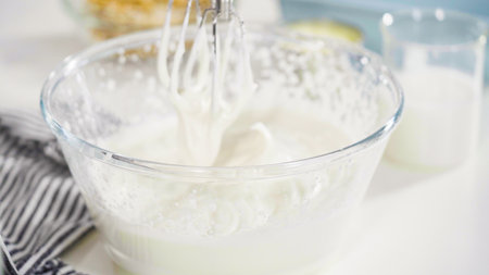 Mixing ingredients in a glass mixing bowl to prepare homemade coconut ice cream.の写真素材