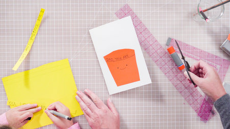 Flat lay. Little girl making a handmade Fathers Day card from construction paper.
