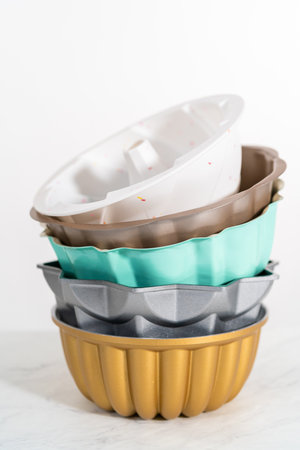 Stack of different colors and shapes bundt cake pans.の写真素材